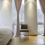Interior de dormitor cu sistem de iluminare interesant de-a lungul zidului cu caramida alba si perdelelor din bumbac gros alb