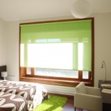 Roleta textila verde asortata cu covor verde shaggy intr-un dormitor mic cu alb si maro